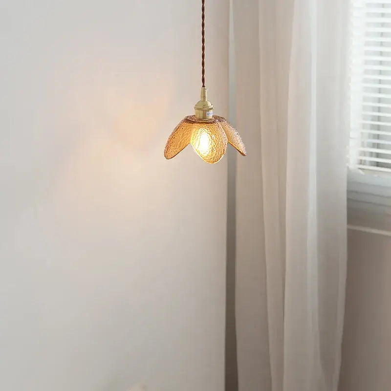 A warm-toned amber glass led pendant light with delicate petal design and brass hardware for kitchen use