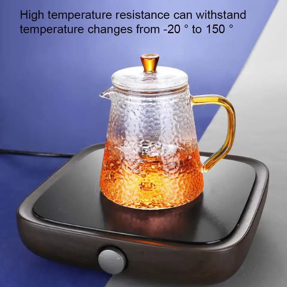 Clear hammered borosilicate glass teapot with amber handle and knob filled with warm tea for kitchen use