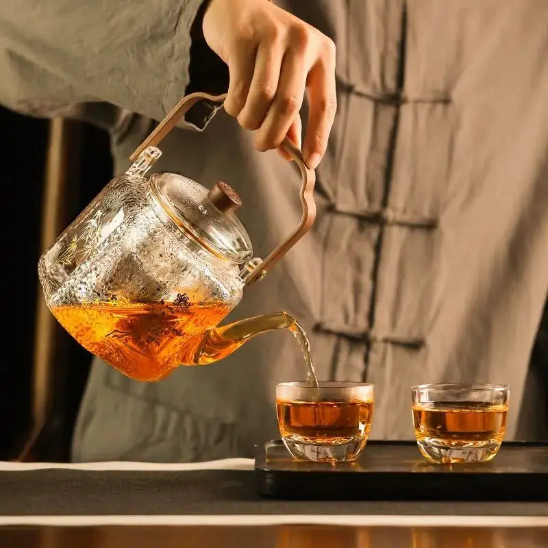 Hammered floral glass teapot with brass handle and lid filled with amber tea by decorbites glass teapot