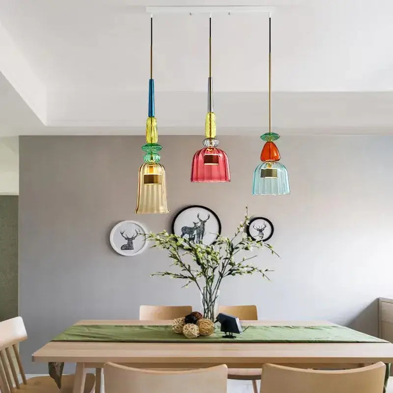 Three colorful hand-blown decorbites candy glass pendant lights with gold accents hang above a dining table