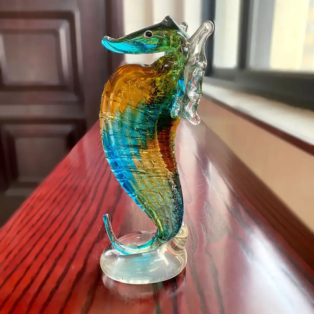 A vibrant hand blown glass seahorse figurine with turquoise amber and green hues for living room decor