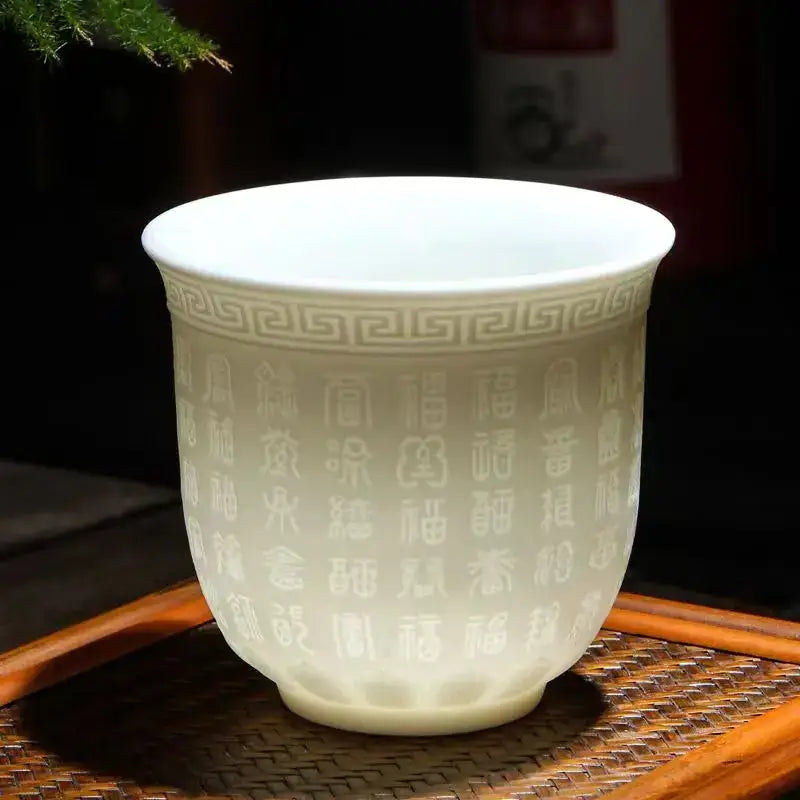 Hand carved translucent white jade ceramic tea cup featuring engraved chinese characters and greek key rim pattern