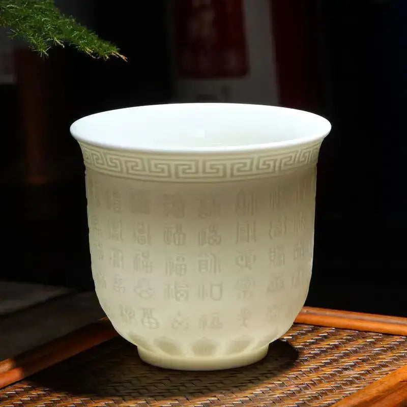 Hand carved translucent white jade celadon tea cup with embossed greek key and chinese characters in a tea cup set