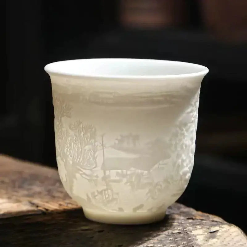 Hand carved translucent white jade tea cup set featuring a delicate etched landscape on a porcelain cup