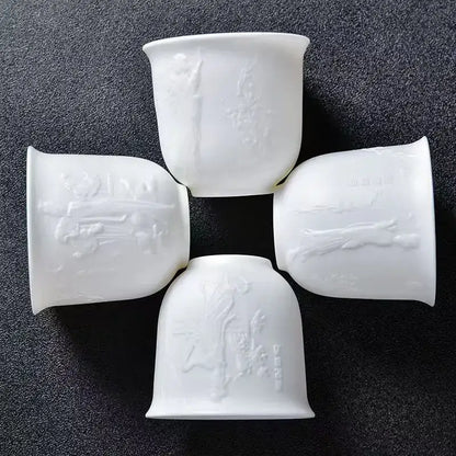 Four white porcelain tea cups with embossed traditional chinese motifs in a hand carved translucent white jade cup set