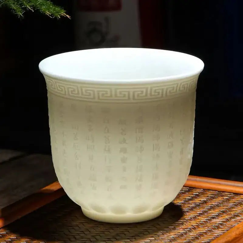 Hand carved translucent white jade tea cup set featuring a celadon porcelain tea cup with greek key pattern and engraved Chinese characters