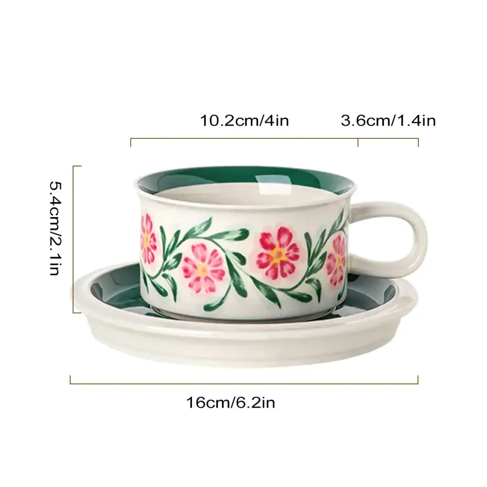 A white ceramic espresso cup with pink floral patterns and green rim on a matching saucer dining room set