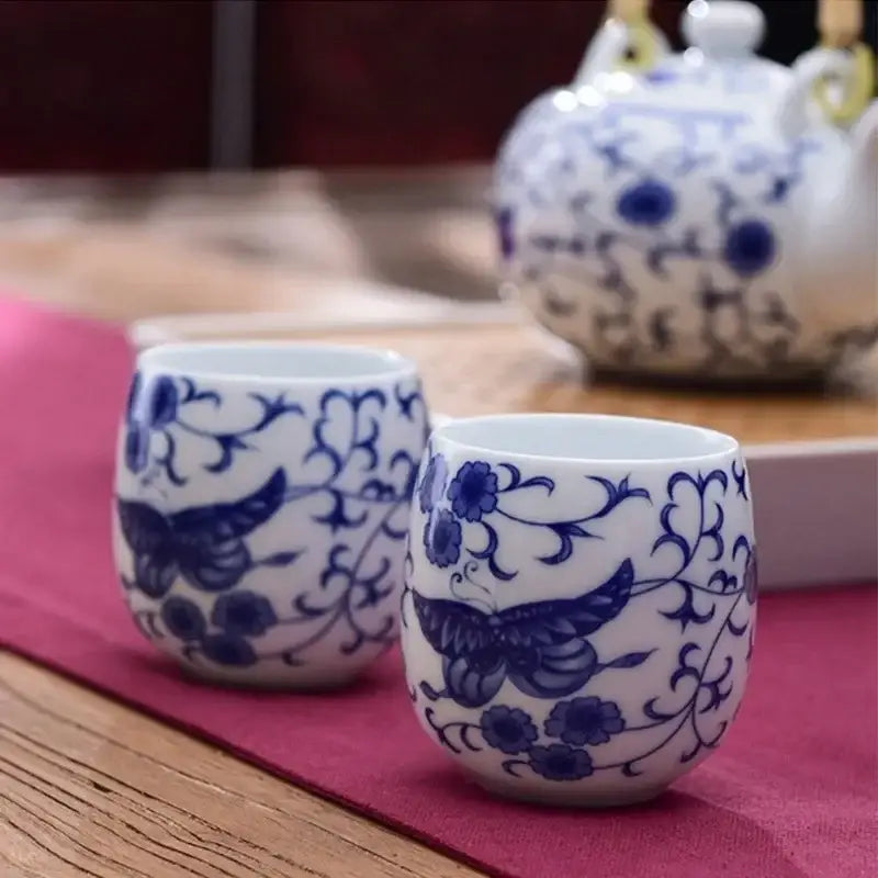 Two white ceramic kung fu tea cups with hand-painted blue floral and butterfly designs for dining room decorbites ceramic kung
