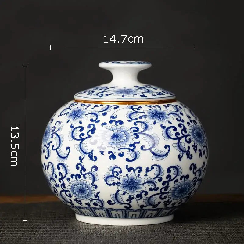 A round white porcelain tea canister with hand-painted blue floral and vine patterns for kitchen storage