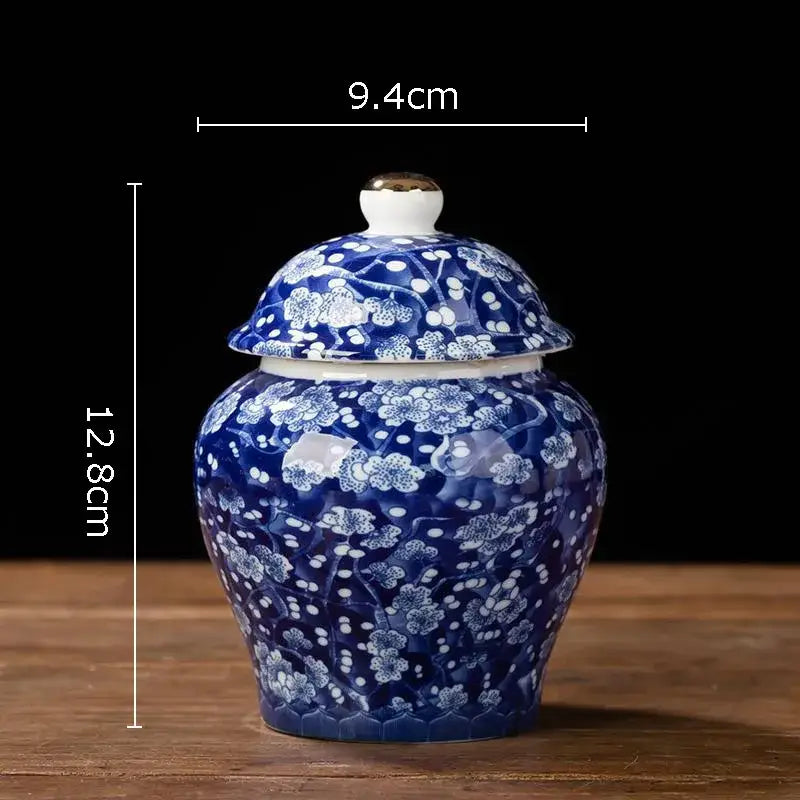 Hand-painted white porcelain tea canister with blue floral pattern and gold-tipped lid for kitchen storage