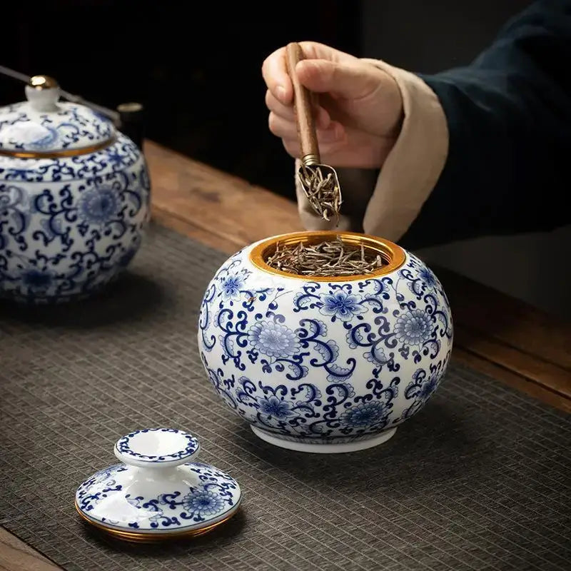 Hand-painted white porcelain tea canister with blue floral patterns and gold-trimmed lid for kitchen storage