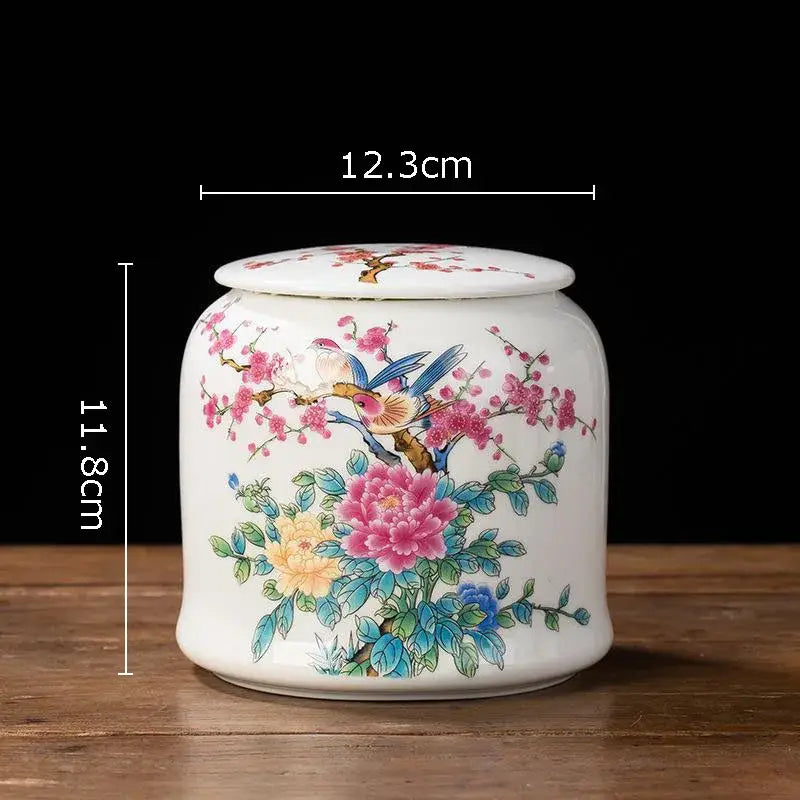 Hand-painted white porcelain tea canister with vibrant pink yellow and blue floral patterns and birds on branches