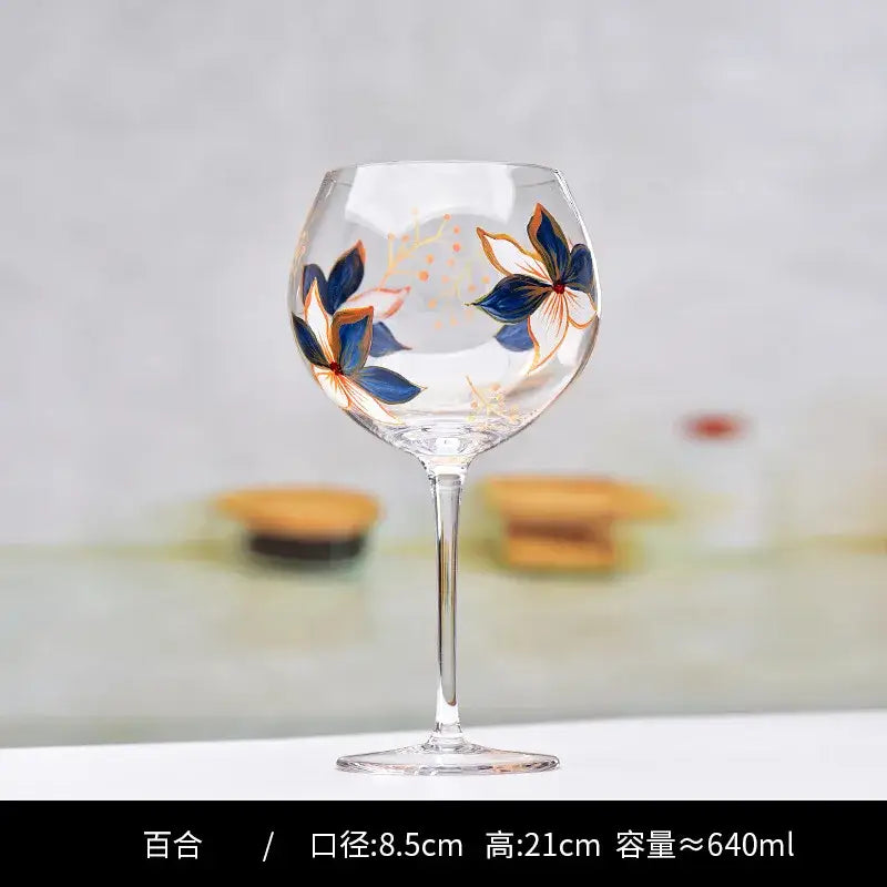 A clear decorbites crystal wine goblet with hand-painted blue and orange floral designs and gold accents