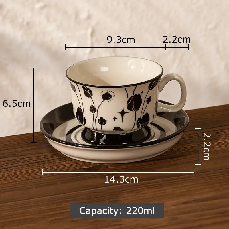 A white ceramic cup and saucer set with black decorbites flowers pattern ideal for dining room use