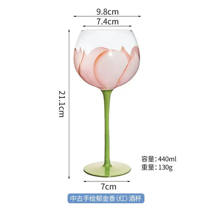 Delicate hand painted glass goblet with pink lotus floral design and slender green stem for elegant dining room decor