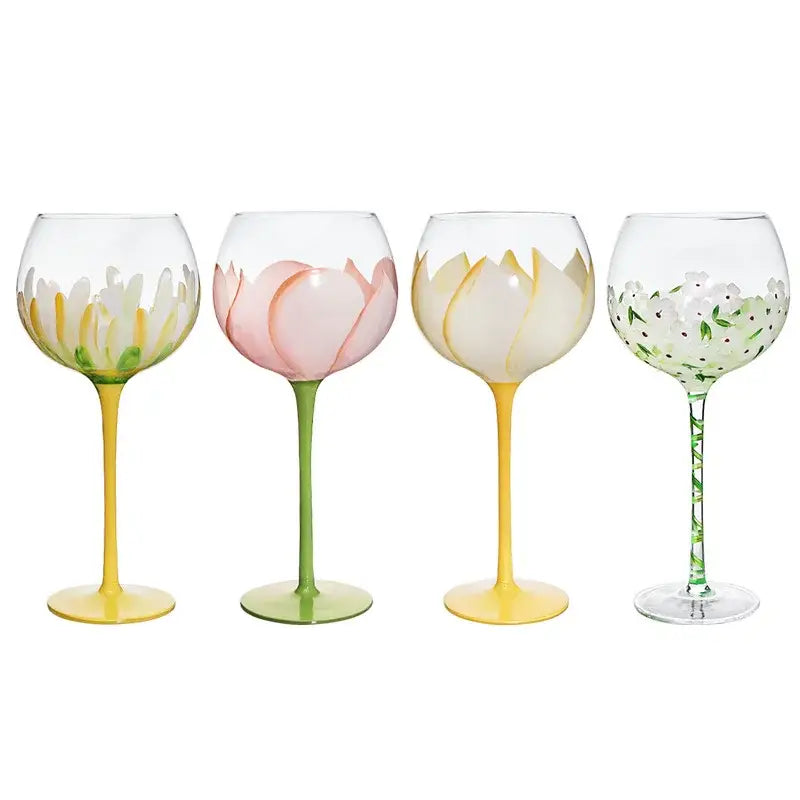 Set of four hand painted glass goblets with pink and yellow floral designs on clear glass and colorful stems