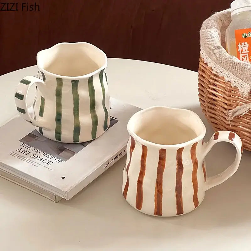 Two hand-painted colorful stripes porcelain mugs in green and brown rest on a table in this kitchen set