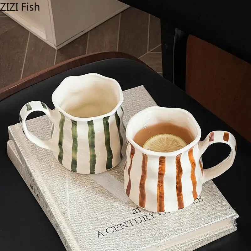 Two hand-painted colorful stripes porcelain mugs in green and brown rest on stacked books decorbites colorful stripes set