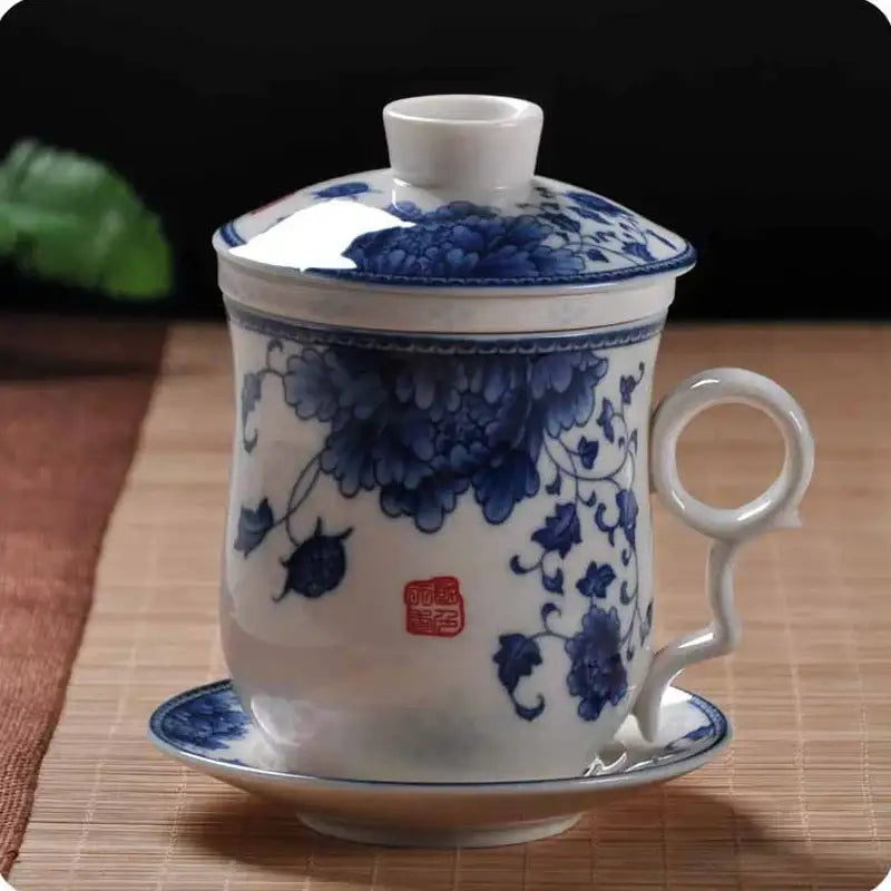 A hand painted white porcelain tea cup with lid and saucer featuring blue floral peony patterns for dining room use