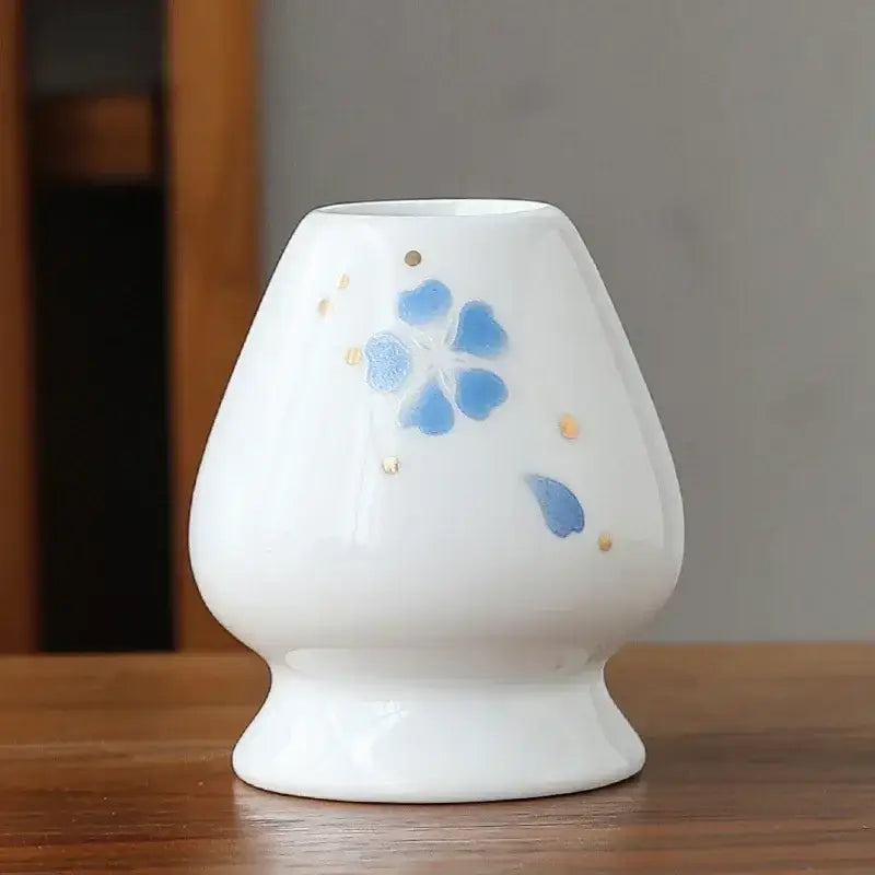Hand painted white ceramic matcha whisk holder stand with blue floral design and gold accents as a whisk holder