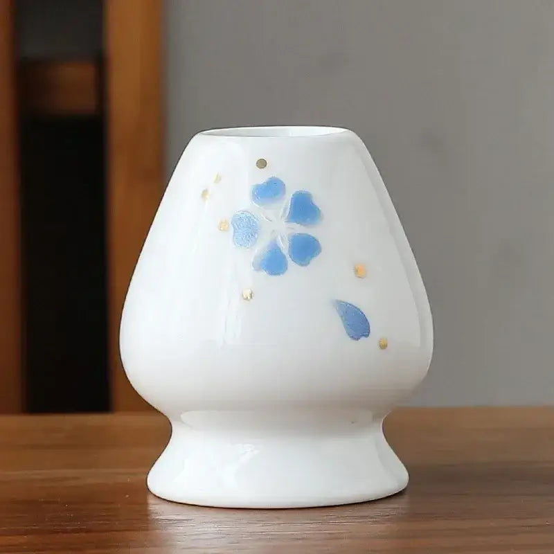White ceramic matcha whisk holder stand with delicate blue floral design and gold accents for whisk storage