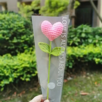 Hand woven love heart yarn crochet pink flower with green leaves in clear plastic sleeve for bedroom decor