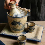 Handcrafted ceramic wine set with speckled beige body and blue fish wave patterns including matching cups and ice vessel