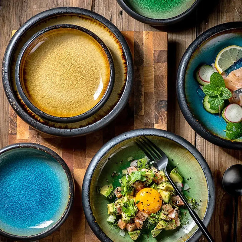 Handcrafted ceramic sushi plate featuring vibrant mustard yellow and teal bowls with rustic black rims for dining use