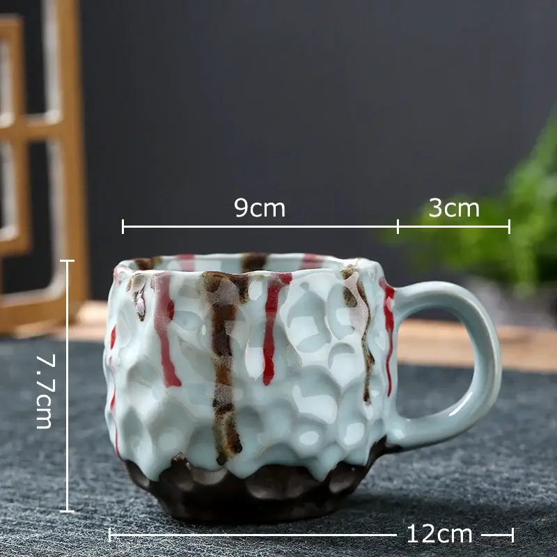 Handcrafted light blue hammer pattern ceramic mug with bold red and brown drips in a dining room ceramic mug set