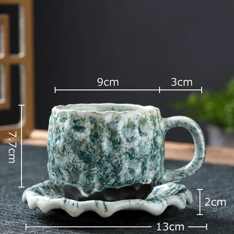 A handcrafted ceramic mug set featuring a textured green and white marbled glaze on a scalloped saucer