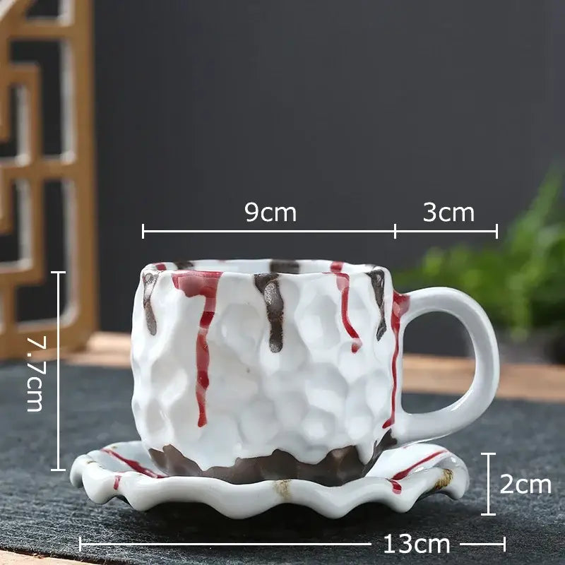 White ceramic hammered teacup with red and brown drips paired with matching saucer in hammer pattern ceramic mug set