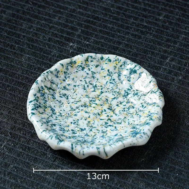 A delicate white ceramic dish with green and yellow speckles complements the handcrafted blue and red hammer pattern ceramic mug set