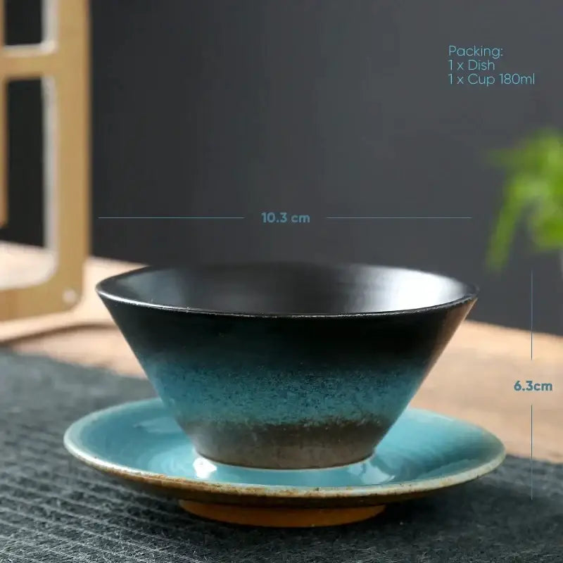 A handcrafted ceramic latte coffee cup and saucer in brown and amber with a gradient glaze from black to turquoise