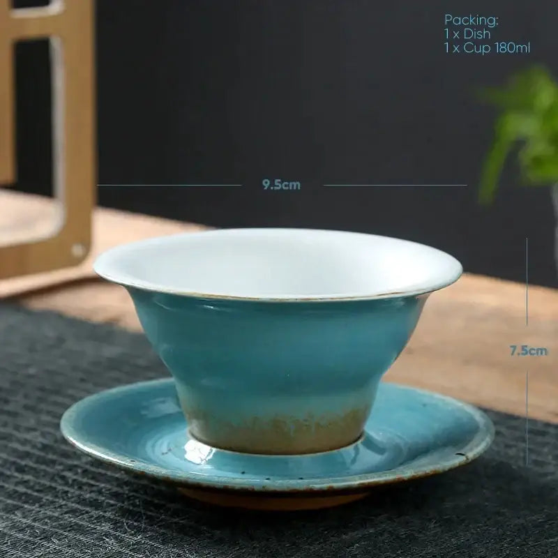 Turquoise ceramic latte coffee cup with white interior and gold rim resting on matching saucer in dining room