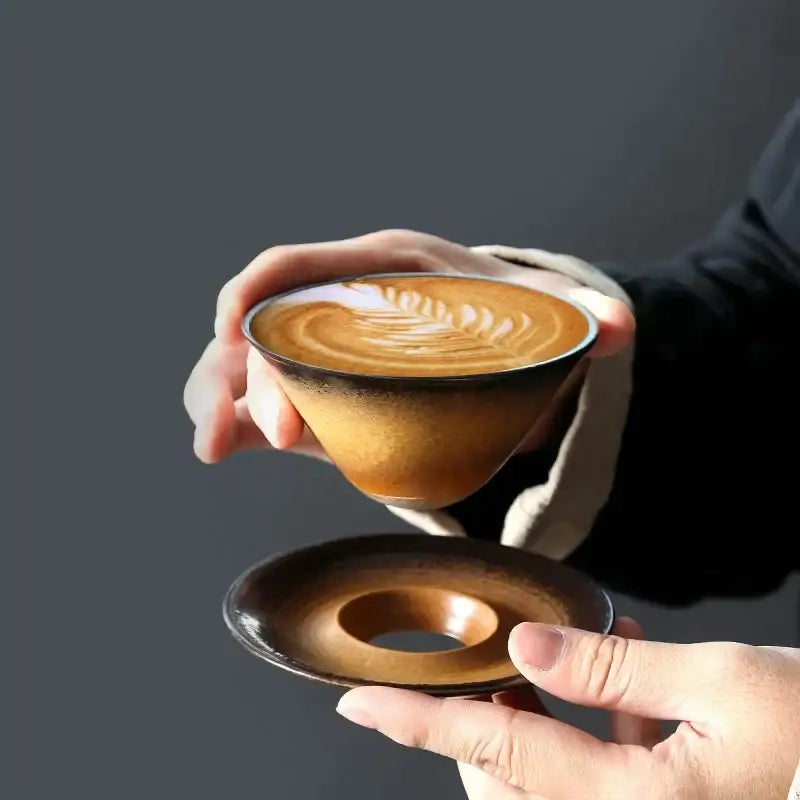 Handcrafted brown and amber ceramic latte coffee cup with gradient glaze and matching donut-shaped saucer for dining room