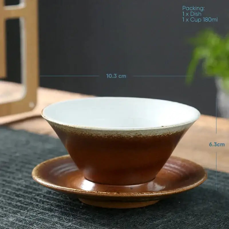 Handcrafted brown ceramic latte coffee cup with white interior resting on matching saucer for dining room use