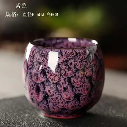 A glossy purple egg style ceramic tea cup with a textured scale-like glaze in a handcrafted tea cup set