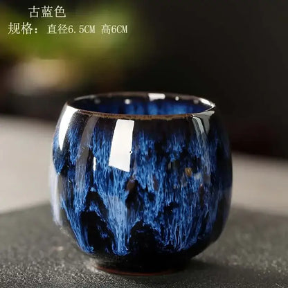 A deep blue glossy egg style ceramic tea cup with swirling textured glaze and flared rim in a handcrafted set