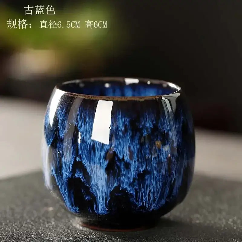 A deep blue glossy egg style ceramic tea cup with swirling textured glaze and flared rim in a handcrafted set