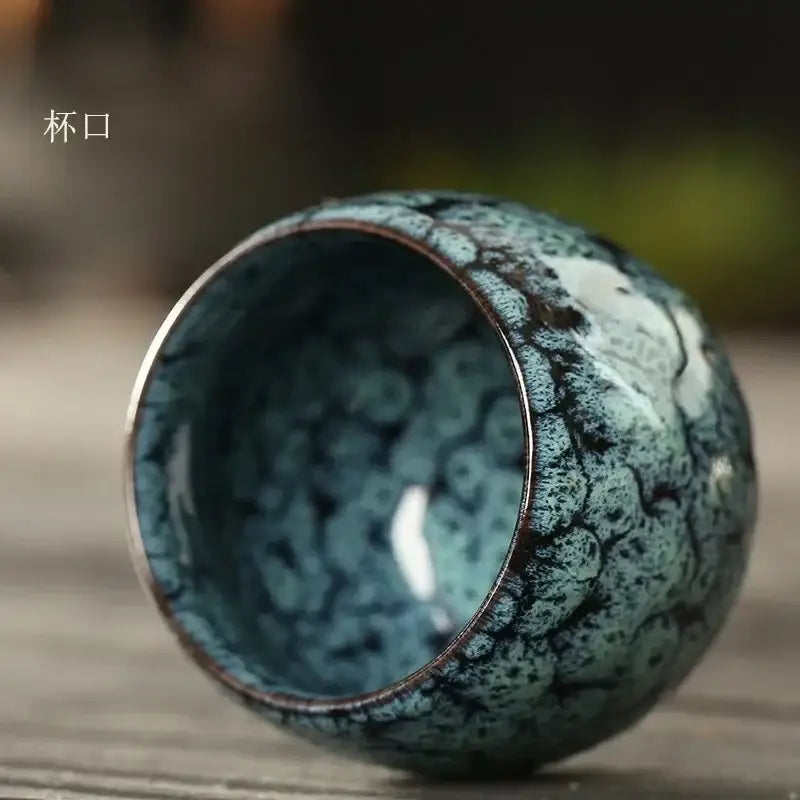 Handcrafted egg style ceramic tea cup with crackled teal and dark brown glaze featuring intricate moss-like patterns