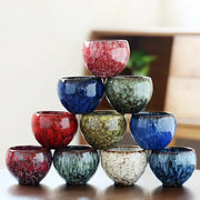 A pyramid of handcrafted ceramic coffee cups with colorful crackle glaze in red blue green and white for dining use