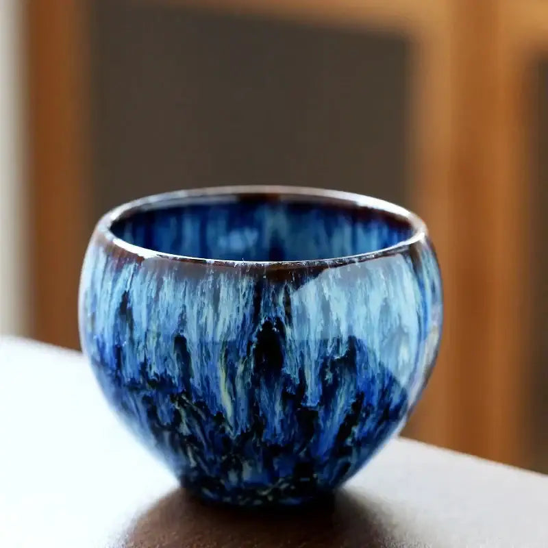 Handcrafted ceramic coffee cup with swirling deep blue glaze and crackle finish for elegant dining room drinkware