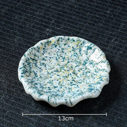 A delicate white scalloped ceramic dish with green and yellow speckles complements hammer pattern porcelain mugs set
