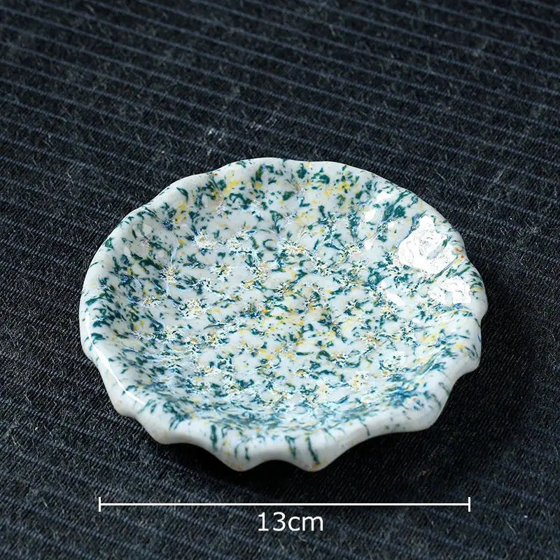 A delicate white scalloped ceramic dish with green and yellow speckles complements hammer pattern porcelain mugs set