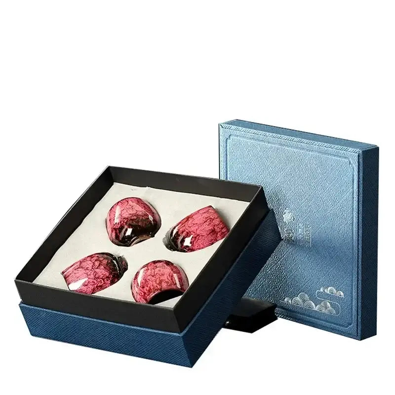 Set of four glossy red handcrafted decorbites ceramic cups with marbled patterns in black-lined blue gift box