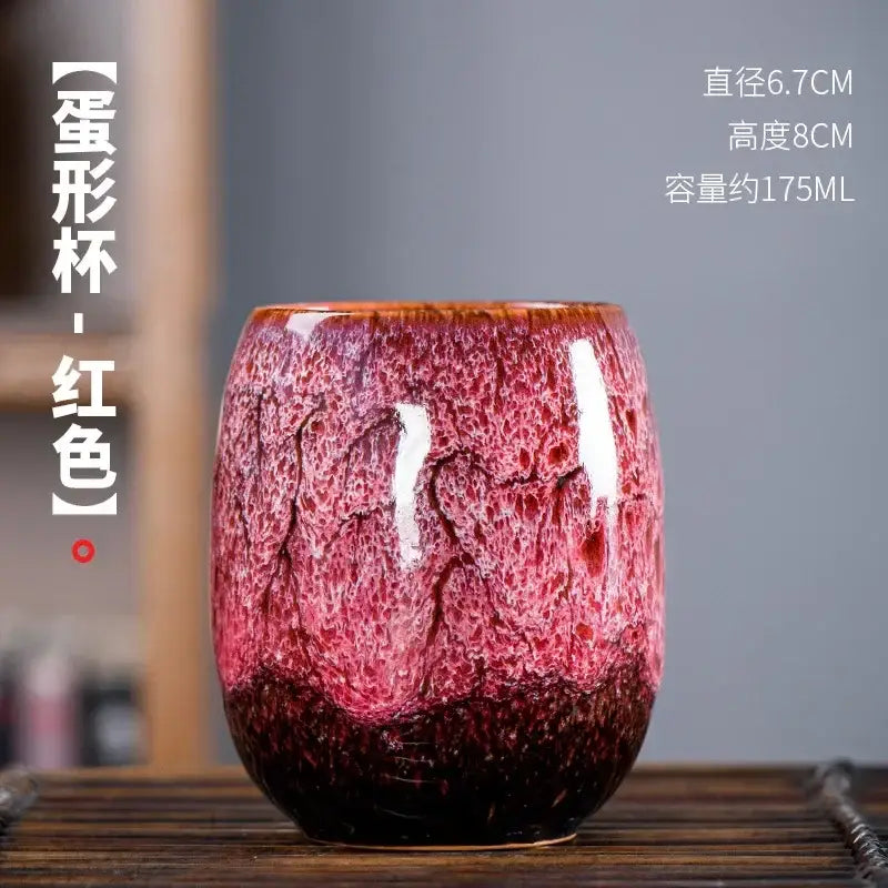 A vibrant red handcrafted ceramic tea cup with crackled glaze and darkened base from a multicolored cup set
