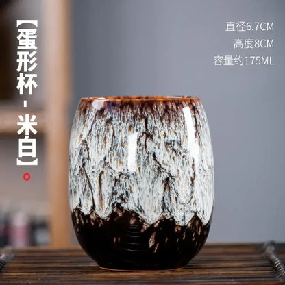 Handcrafted ceramic tea cup with glossy marbled white and dark brown glaze from a multicolored cup set