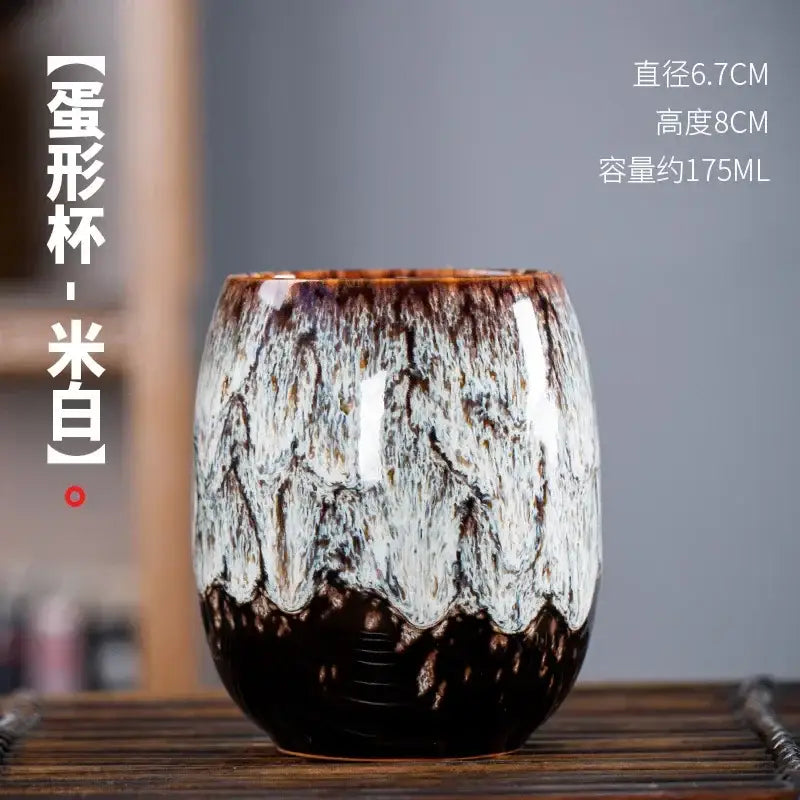 Handcrafted ceramic tea cup with glossy marbled white and dark brown glaze from a multicolored cup set