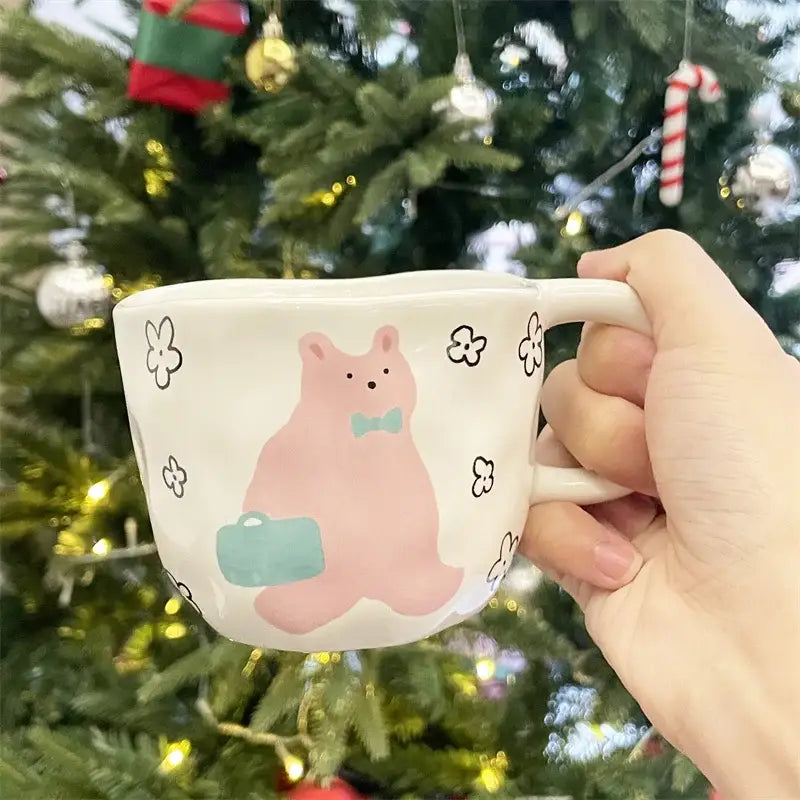 Handcrafted white ceramic bear mug featuring a pink bear with a bow tie and suitcase surrounded by black flowers