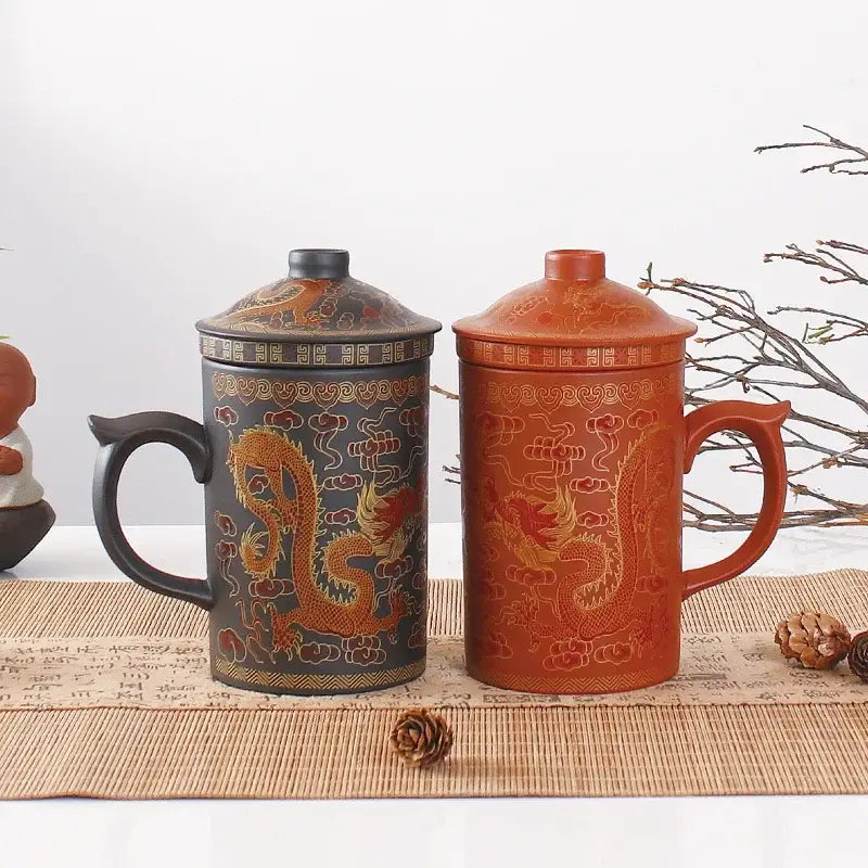 Two ceramic tea mugs with lids in dark gray and terracotta orange featuring golden dragon decorbites dragon purple clay designs